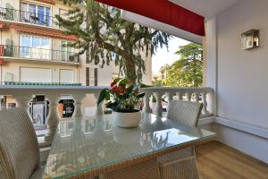 une table avec des chaises et une plante sur un balcon dans l'établissement Hotel Le Fouquet's, à Cannes