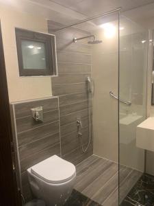 uma casa de banho com um WC e uma cabina de duche em vidro. em City Rose Hotel Suites em Amã