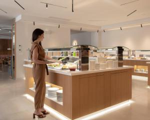 una mujer parada en una cocina preparando comida en Bio Suites Hotel & Spa, en Rethymno