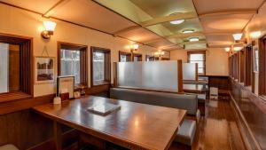 Shokudo and Hotel Kisyapoppo في Nakatsu: قاعة اجتماعات مع طاولة وكراسي خشبية