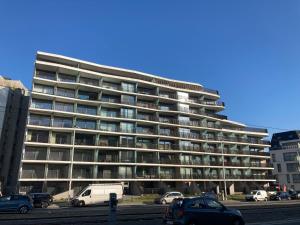 a large building with cars parked in a parking lot at luxestudio - zeezicht - groot terras - zwembad in Ostend