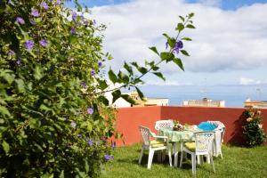 a table and chairs in a yard with purple flowers at Live Santa Úrsula Cala in Santa Úrsula