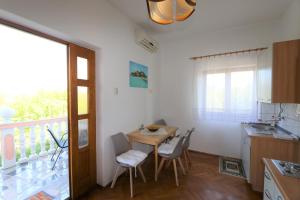 eine Küche mit einem Tisch und Stühlen sowie einen Balkon in der Unterkunft Apartment Zinka in Šilo