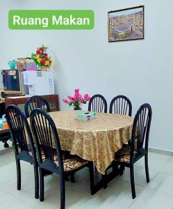 a dining room table with four chairs and a tableablish at Homestay Intan Anjung Lodge in Melaka