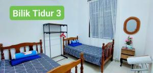 two twin beds in a bedroom with words billing tutor three at Homestay Intan Anjung Lodge in Malacca