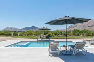 a swimming pool with two chairs and an umbrella at Villa Nikoli in Kolymbia