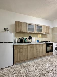 a kitchen with wooden cabinets and a white refrigerator at Arya Seaview Escape Balcony & Beach Walk in Coral Bay
