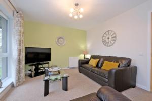 a living room with a leather couch and a flat screen tv at Caledonia Netherhills Apartment in Aberdeen