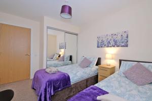 a bedroom with two beds and a mirror at Caledonia Netherhills Apartment in Aberdeen