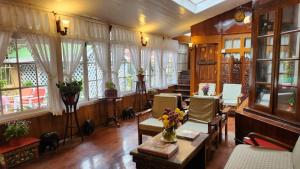 uma sala de estar com cadeiras, janelas e uma mesa em Ivanhoe Hotel (A Heritage Property) em Darjeeling