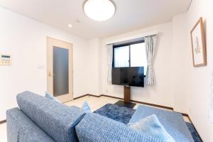 salon z niebieską kanapą i telewizorem w obiekcie Minami-Aoyama-1st w Tokio