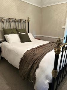 a bedroom with a large bed with white sheets and pillows at Ulva Cottage - Historical BnB in Penola