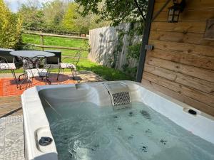 a hot tub in a backyard with a table and chairs at Aux murmures de la nature in Honfleur