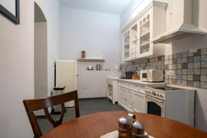 a kitchen with white appliances and a wooden table at Kinsley Apartament 2 in Timişoara