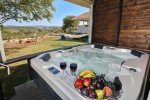 a hot tub with a bowl of fruit and two glasses of wine at Biktot Nofim in Manot