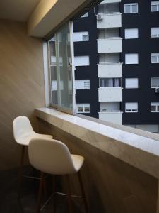twee witte stoelen voor een raam bij House of Mac Apartments in Niš