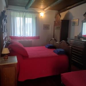 1 dormitorio con cama roja y ventana en Locanda La Posta, en Castel dʼAiano