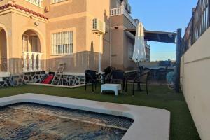 adosado con piscina a 10 minutos de Alicante في أليكانتي: حديقه خلفيه بها مسبح ومنزل