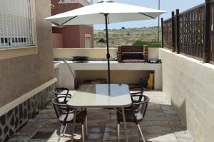 een witte tafel en stoelen met een parasol op een balkon bij adosado con piscina a 10 minutos de Alicante in Alicante