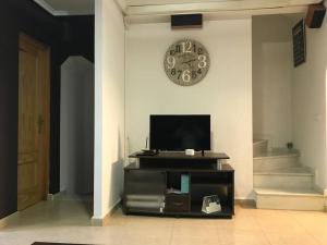 a living room with a tv and a clock on the wall at adosado con piscina a 10 minutos de Alicante in Alicante