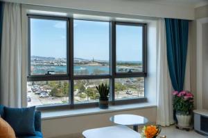 una sala de estar con una gran ventana con vistas al agua en Cloud & Sea Boutique Apartment en Rizhao