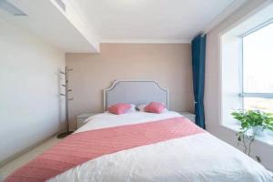 a bedroom with a large bed with two pink pillows at Cloud & Sea Boutique Apartment in Rizhao