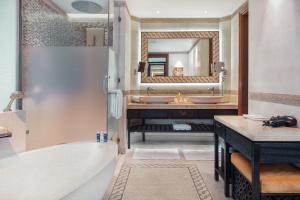 uma casa de banho com uma banheira, um lavatório e um espelho. em Banana Island Resort Doha by Anantara em Doha