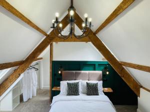a bedroom with a bed and a chandelier at THE APPLE LOFT - Rustic luxury one bed cottage in Strete