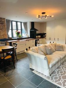 een woonkamer met een witte bank in een keuken bij THE APPLE LOFT - Rustic luxury one bed cottage in Strete