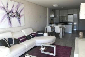 a living room with a white couch and a kitchen at Green Hills 1-2 in Orihuela