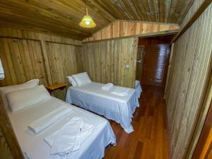 two beds in a room with wooden walls and wood floors at Tree Houses Hotel in Fethiye