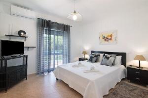- une chambre blanche avec un lit et une télévision dans l'établissement Apartamento Kaya, à Albufeira
