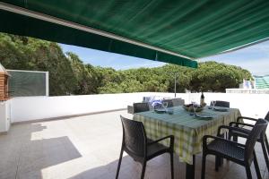 - une table avec des chaises et un auvent vert sur la terrasse dans l'établissement Apartamento Kaya, à Albufeira