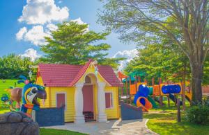 un parque infantil con una pequeña casa amarilla y rosa en Mavsa Resort en Cesário Lange