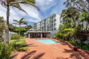 an apartment building with a swimming pool and palm trees at Chaka's Cove 66 in Ballito