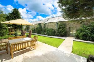 un patio con mesa y sombrilla en Trevadlock Manor Self Catering Cottages, en Launceston