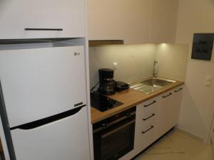 a kitchen with a white refrigerator and a sink at Modern lifestyle flat close to the sea. in Gázion