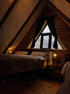 a room with two beds in a attic with a window at Kazbegi Hut Cottage in Stepantsminda
