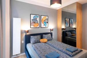 a bedroom with a bed with blue pillows and a mirror at Golden Apartments Sokolska 30 Towers&59 in Katowice