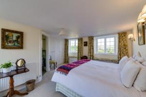 um quarto com uma grande cama branca e janelas em Trevadlock Manor Self Catering Cottages em Launceston