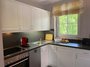 eine Küche mit weißen Schränken und einer Spüle und einem Fenster in der Unterkunft Haus Kranich App 422 in Dierhagen