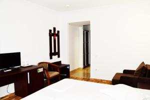 a bedroom with a bed and a desk and a couch at Puflene Resort in Murighiol