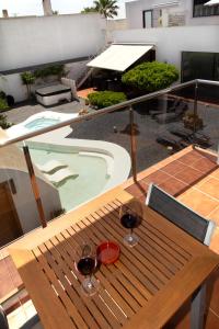 two glasses of wine sitting on a wooden table on a balcony at Hotel Mar d'Espills - Adults Only in El Poblenou del Delta