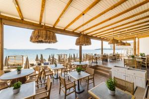 ein Restaurant mit Tischen und Stühlen und Meerblick in der Unterkunft Skiathos Thalassa Cape, Philian Hotels and Resorts in Megali Ammos