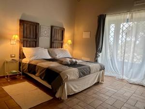 a bedroom with a large bed and a large window at Masseria Santacatrini in Melilli