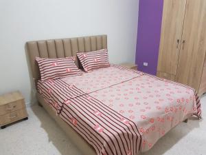 een bed met roze en witte lakens en kussens bij Djerba La Douce in Houmt Souk