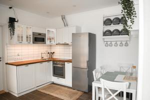 a kitchen with white cabinets and a table and a refrigerator at Bodrogpart Vendégház Tokaj in Tokaj