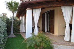 a house with white drapes on the side of it at Sweet House in Villasimius