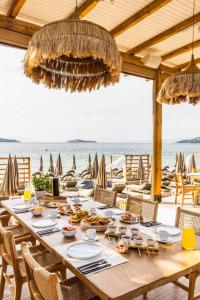 una larga mesa de madera con comida en la playa en Skiathos Thalassa Cape, Philian Hotels and Resorts, en Megali Ammos