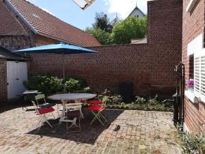 eine Terrasse mit einem Tisch, Stühlen und einem Sonnenschirm in der Unterkunft Le repos bien mérité in Nesle